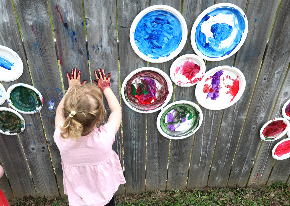 A child puts her handprints on the fence during outdoor play time.