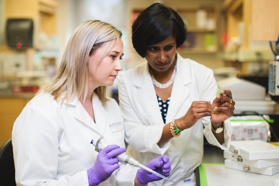 Two women wearing lab coats in a lab