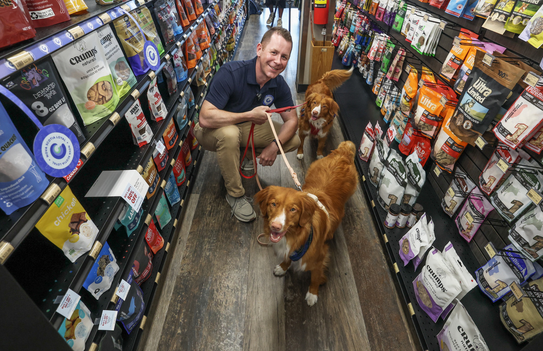 Growth and Development Minister Colton LeBlanc with two Nova Scotia Duck Tolling Retrievers at a specialty pet store