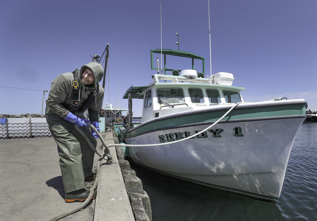 A person on a wharf with a rope to a fishing boat