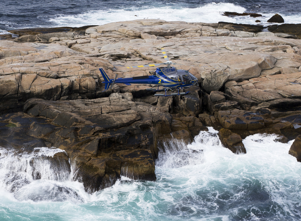 A helicopter flying near a rocky coastline