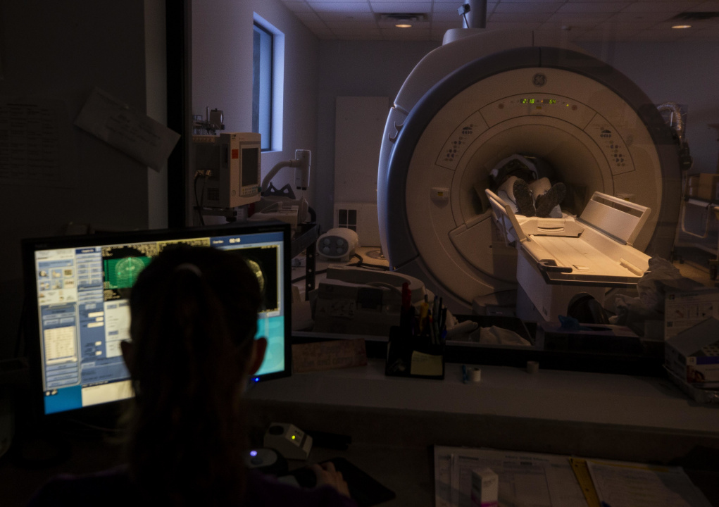 A healthcare worker performs a CT scan on a patient.