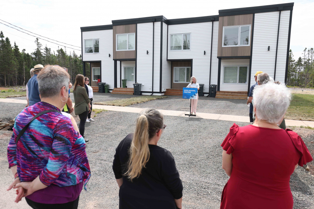 A woman at a podium outside a housing unit