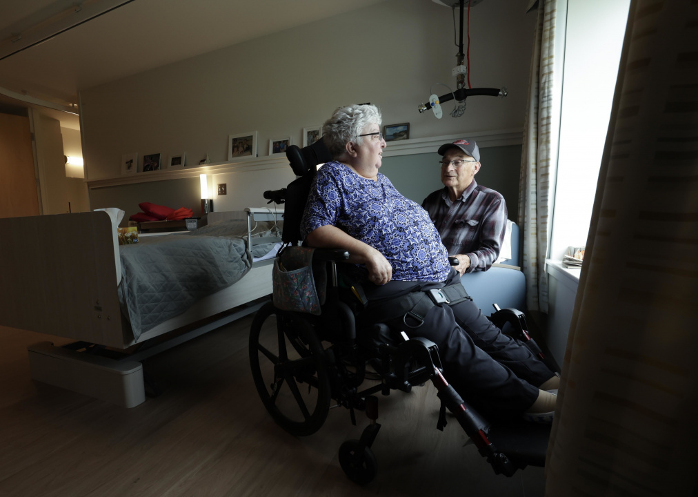 A woman in a wheelchair and a man talking in a long-term care room