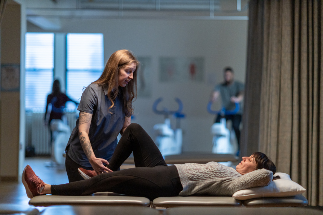 A physiotherapist works with a client lying on a table