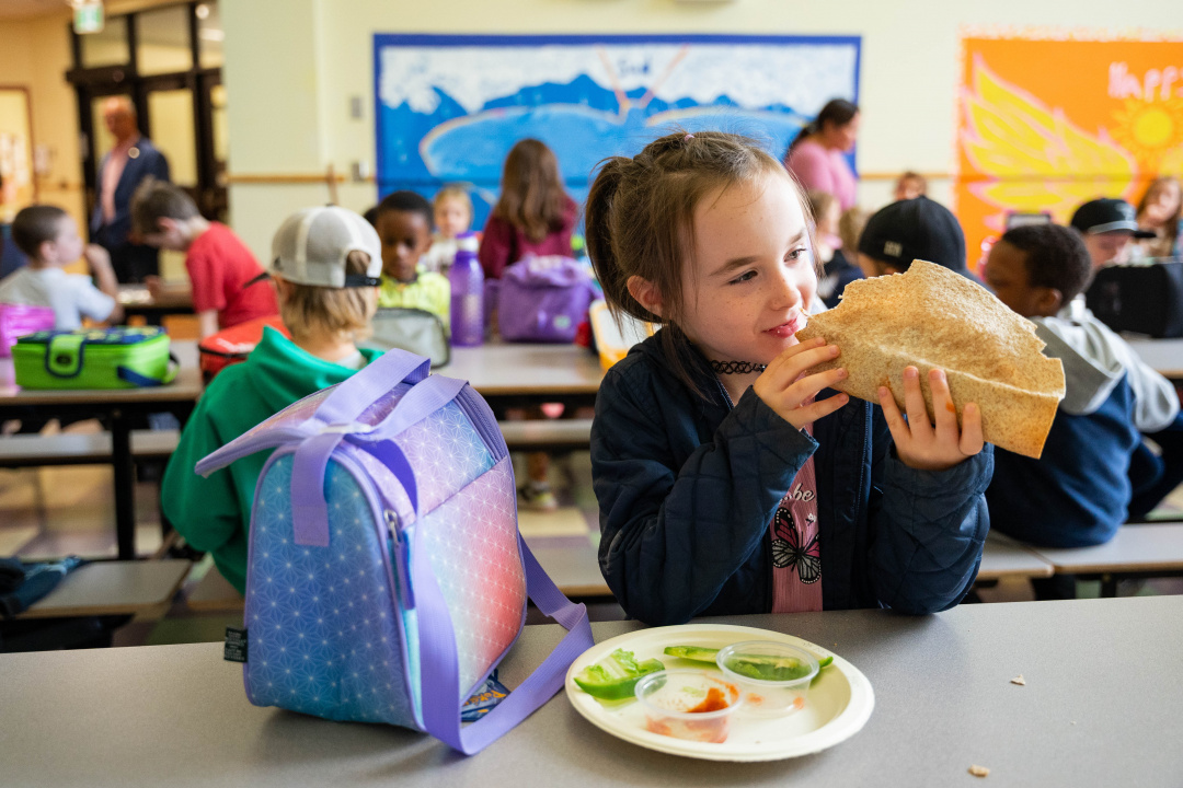 A student eats a taco in her school lunch room.