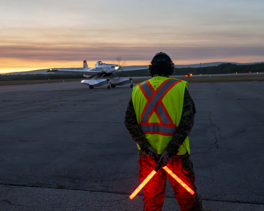 fire fighting plane on airstrip at dusk with air traffic controller standing nearby