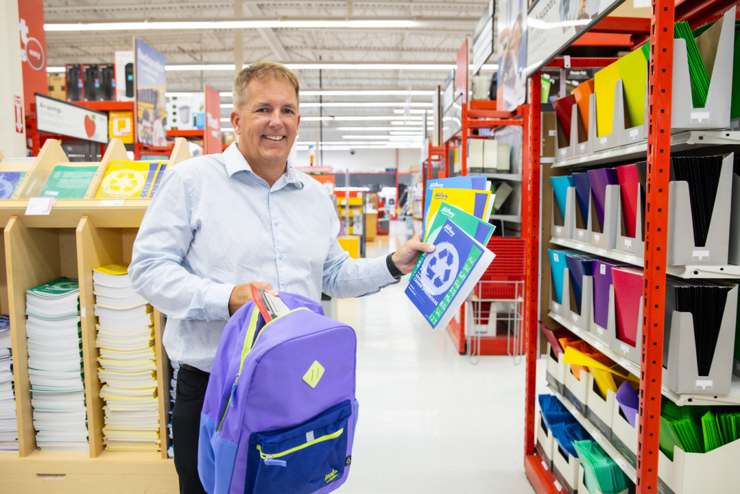 Opportunities and Social Development Minister Armstrong holds a backpack and notebooks in a Staples store