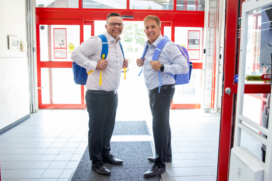 Education and Early Childhood Development Minister Brendan Maguire and Opportunities and Social Development Minister Scott Armstrong wear backpacks in a Staples store