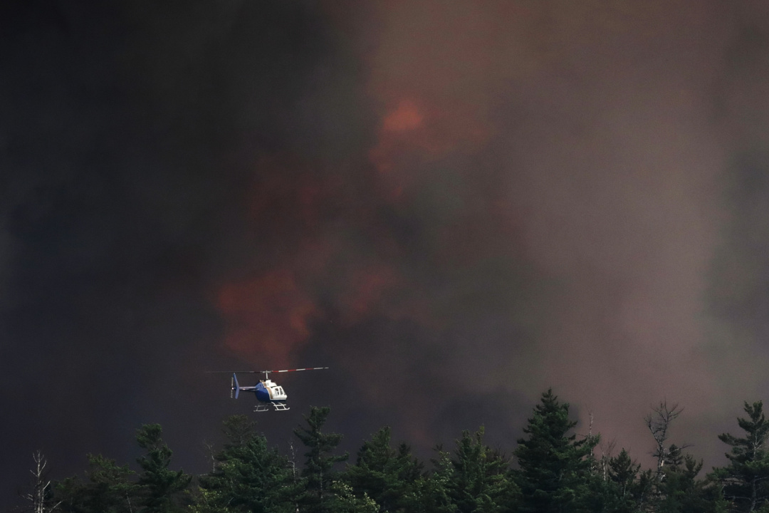 A contracted helicopter moves toward the Long Lake wildfires complex, gathering intelligence and guiding other contracted helicopters where to drop water.
