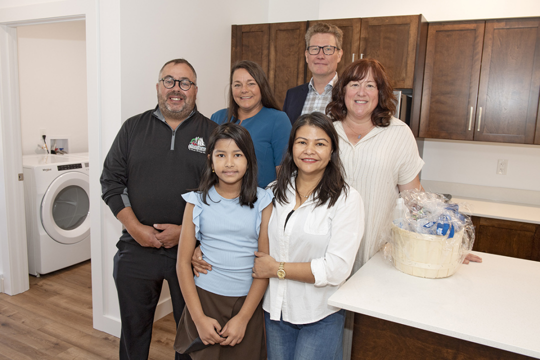 New residents pose for a photo with participants from the announcement in their kitchen.