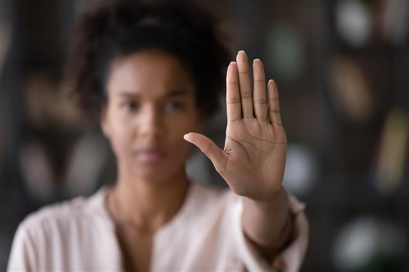 A woman holding her hand out, indicating stop.