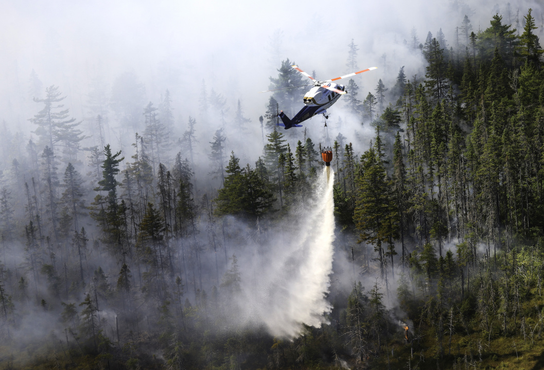 A contracted helicopter drops water on the Long Lake wildfires complex.