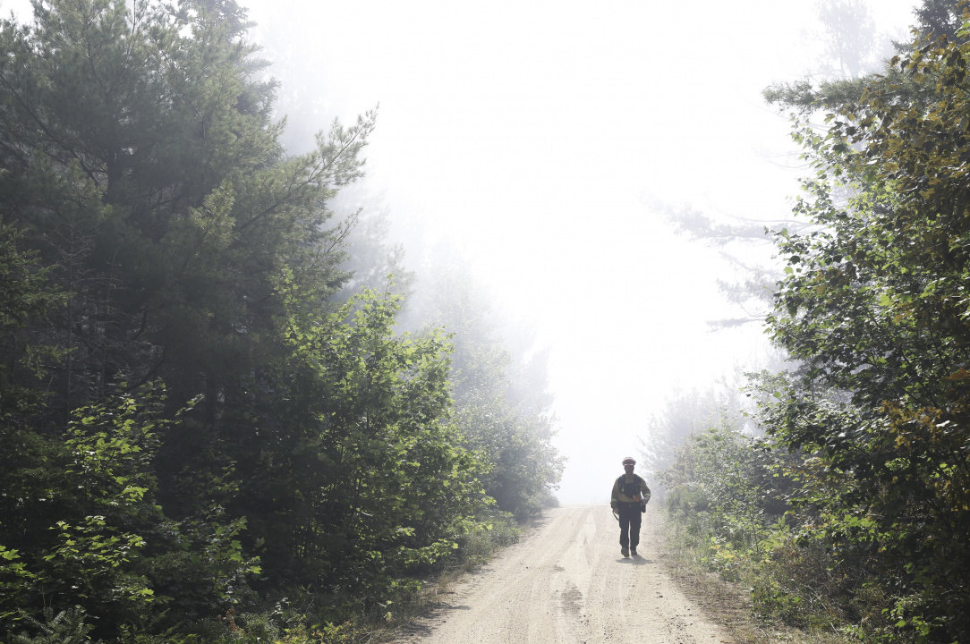 Natural Resources firefighter Christian Nickerson of Tusket walks down a road in the woods, away from the fire scene. 