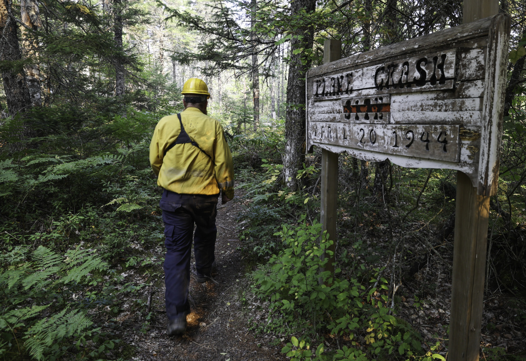 Division Supervisor Cory Isenor of Falmouth walks past a sign in the woods marking the memorial site of a 1944 plane crash. Firefighters were able to save the memorial site from the wildfire. 