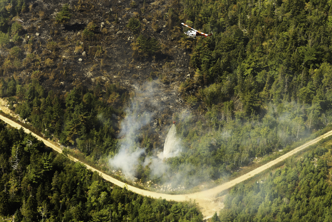 Aerial photo of a helicopter dropping a load of water with pinpoint accuracy on the fire near Paradise Lake.