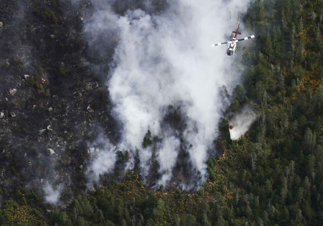 Aerial photo of a helicopter dropping a load of water with pinpoint accuracy on the fire near Paradise Lake.