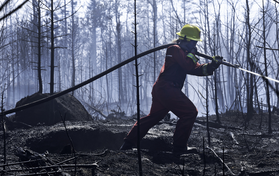 Fire fighter sprays burnt area