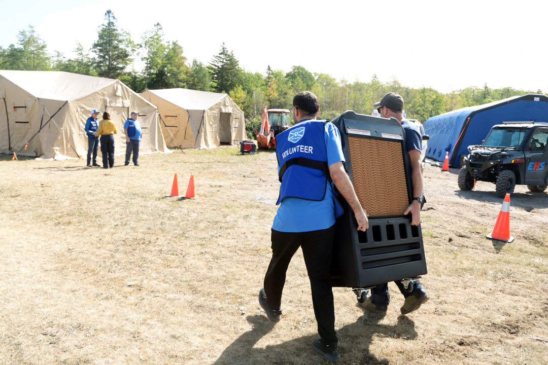Nova Scotia Guard member helps move an air conditioner unit to the tents in the parking lot of the wildfires command post at the West Dalhousie Community Centre.