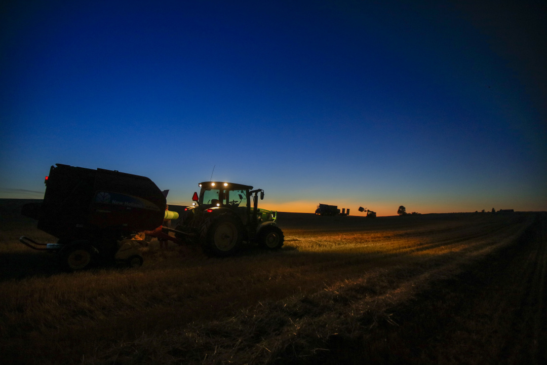 Farmers and equipment at work as the sun goes down.
