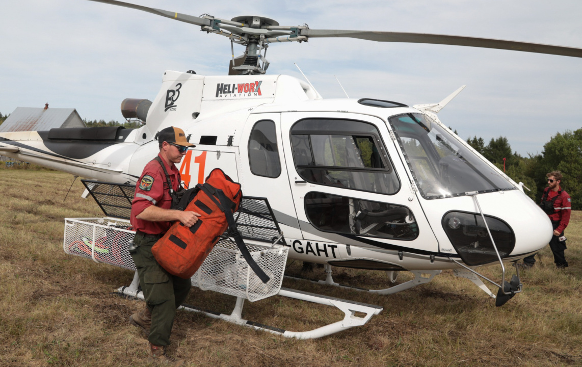 Ontario firefighter Kenny Cox unloads equipment from a helicopter at the staging area.
