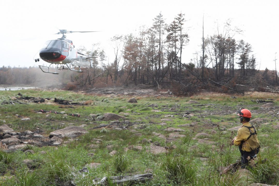 Nova Scotia Strike Team Leader Mike LeBlanc guides a helicopter onto a landing area where his crew is working at Paradise Lake.