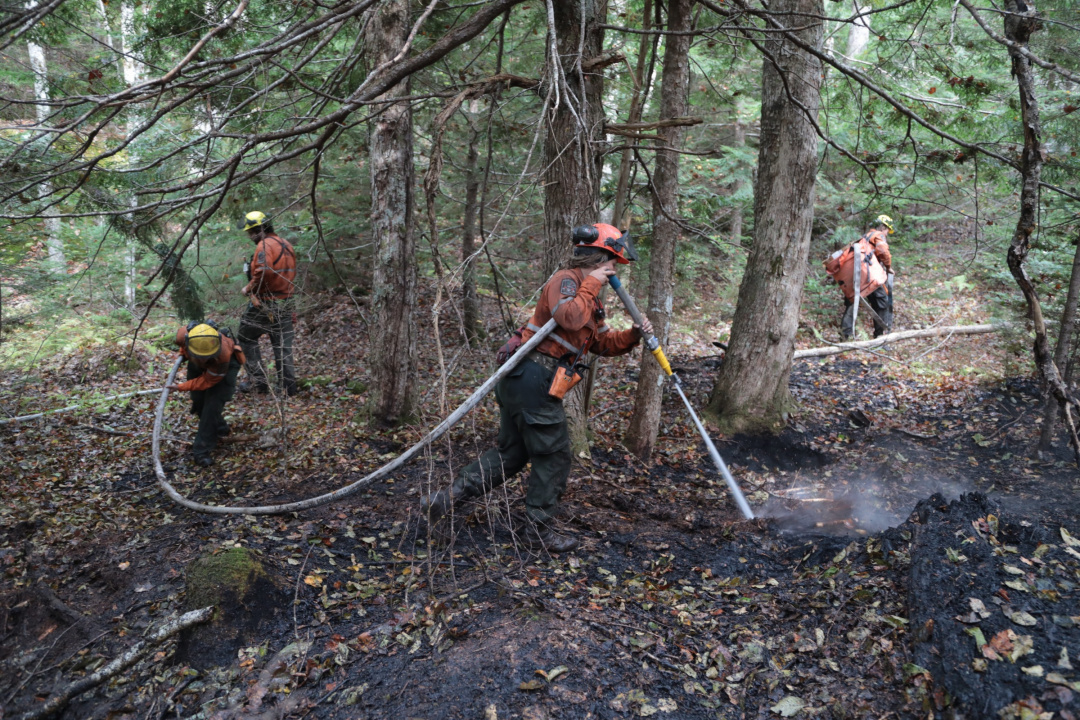 Ontario Crew Leader Neve McKay (L) and Rachel Haavaldsrud spray into the soil and roots of smouldering trees at Paradise Lake