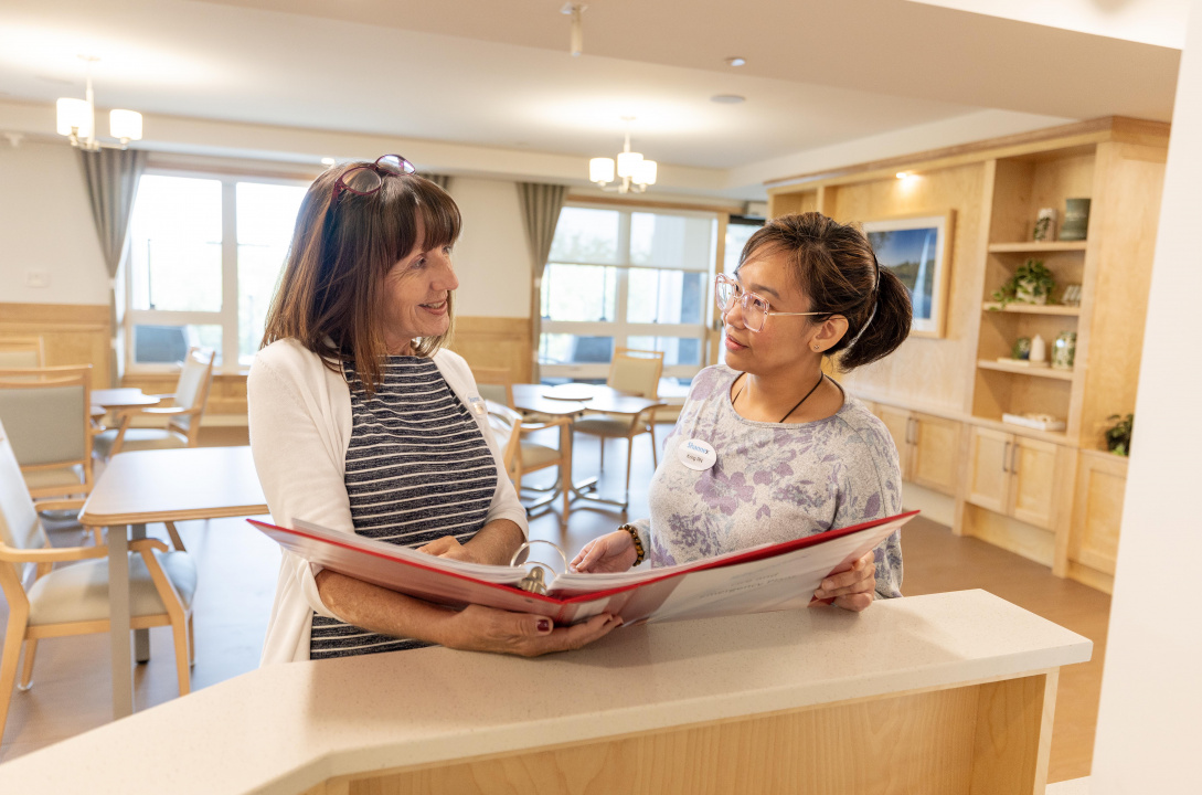 Two registered nurses talking at a desk of a new long-term care home
