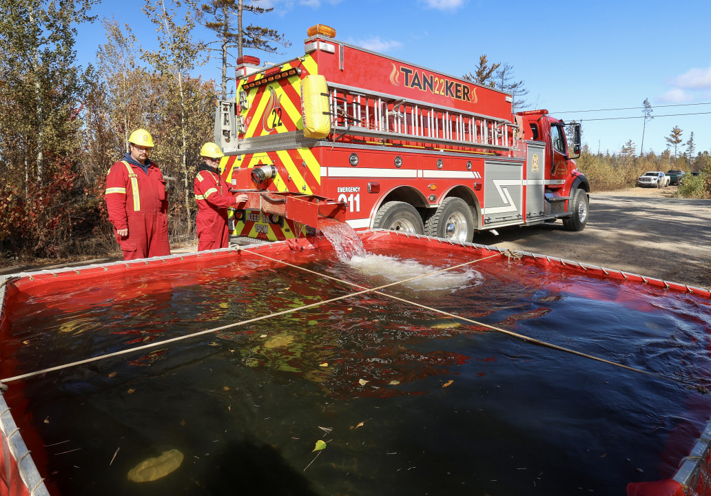 Graeme Sanford (right) and Jeremy VanDenhof, both Bewrick volunteer firefighters, fill the water bladders that the crews draw from