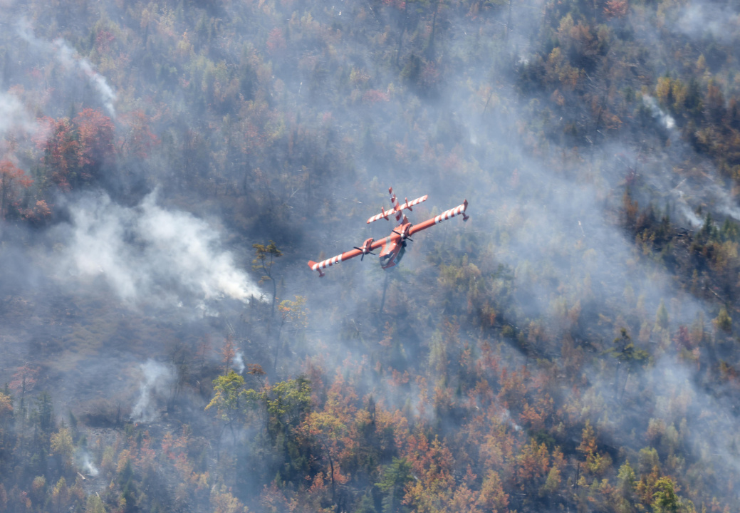 Aerial photo of a plane over the Lake George wildfire with smoke below