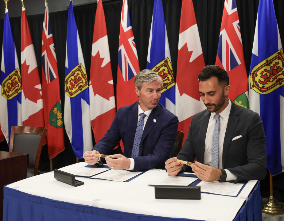 Premier Tim Houston and Ontario Minister Stephen Lecce at a table preparing to sign documents