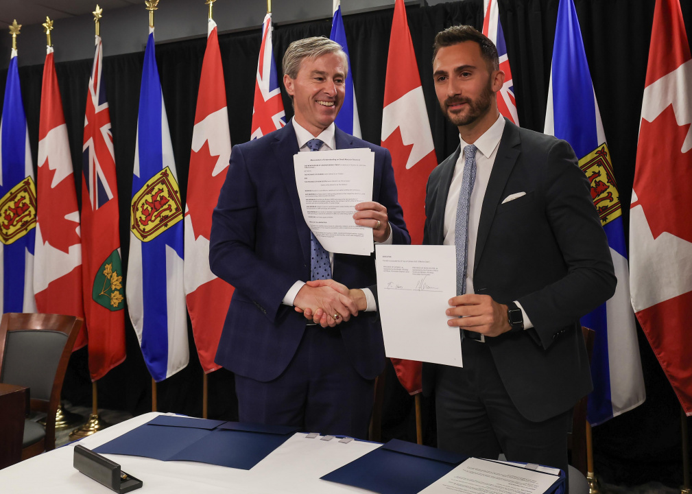 Premier Tim Houston and Ontario Minister Stephen Lecce shake hands while holding copies of an MOU