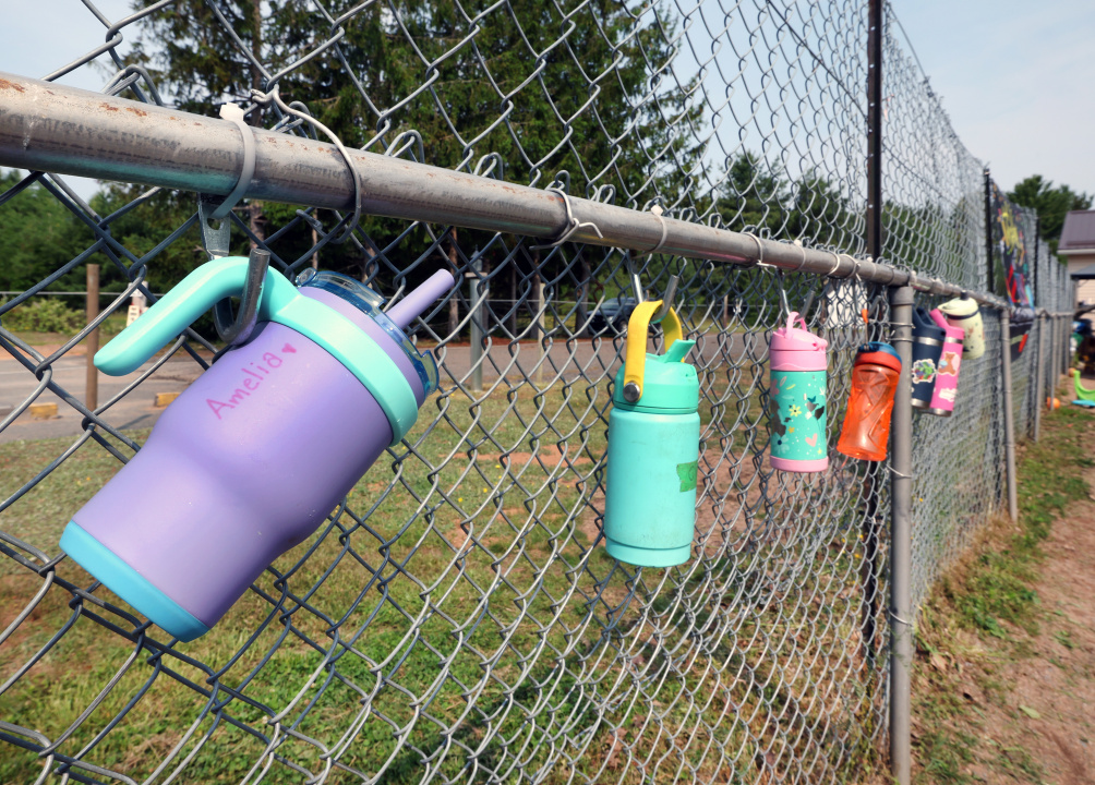 An array of water bottles on a fence by a child-care centre.
