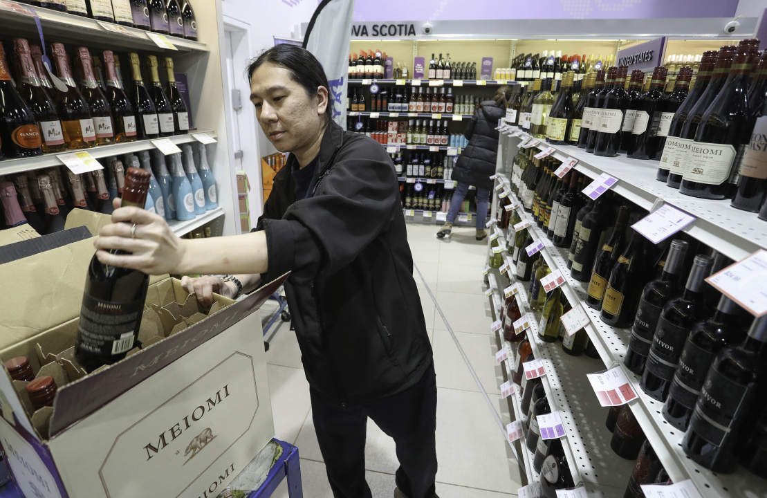 An NSLC worker putting a bottle of wine in a box