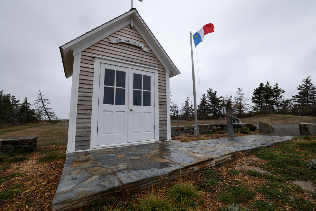 A tiny historic chapel and Acadian flag on a flagpole in the background