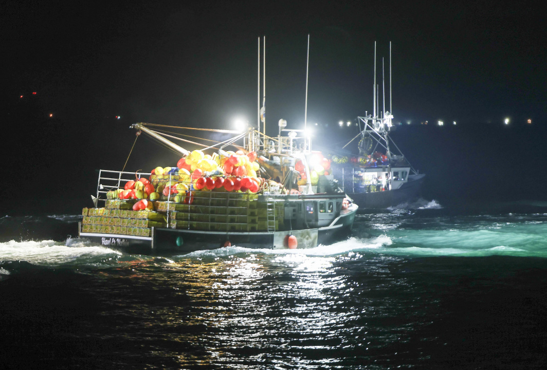 A lobster fishing boat has its lights on in the dsrk