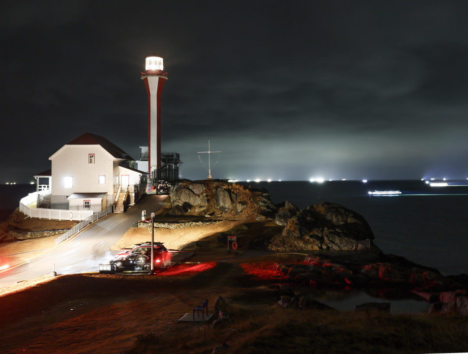 Ships from Southwestern Nova Scotia round Cape Forchu and a lighthouse with the light on