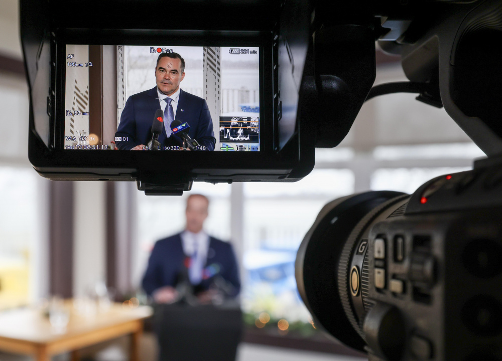 Fisheries and Aquaculture Minister Kent Smith at a podium, seen through a TV camera viewfinder