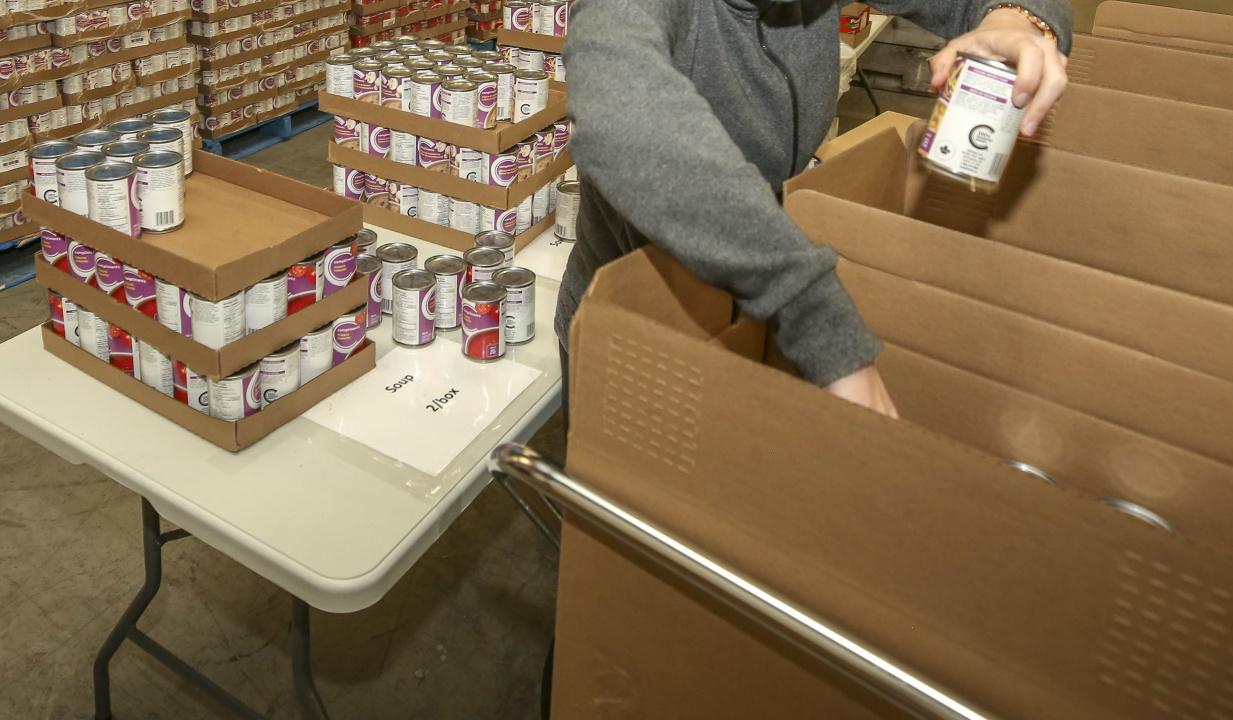 A person's hands are shown packing boxes with food.
