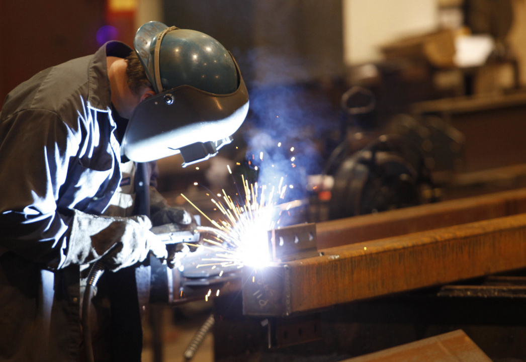 A worker wearing a helmet welds.