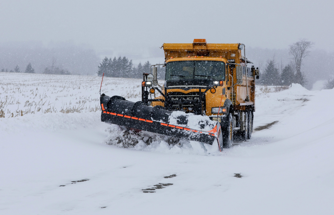 A snowplow plows a snow covered road