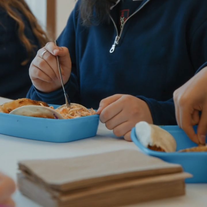 A person’s hand holding a fork as they prepare to eat from a reusable container