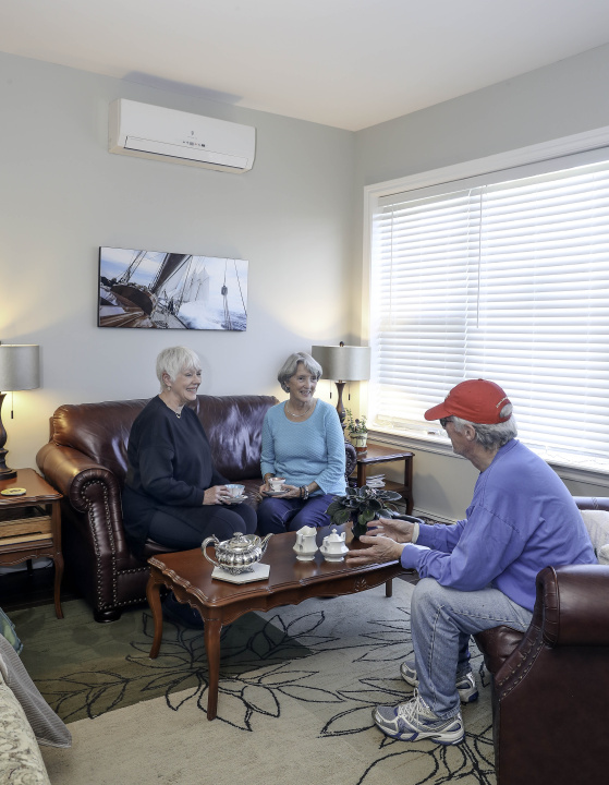 Seniors sitting in a room with a heat pump.