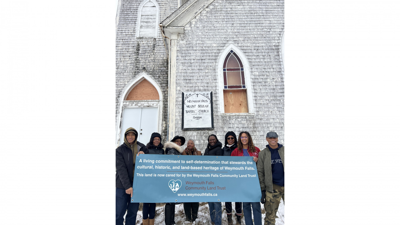 People holding a sign in front of a church
