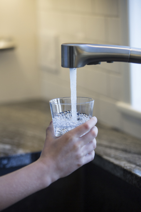 Someone getting a glass of water from a tap