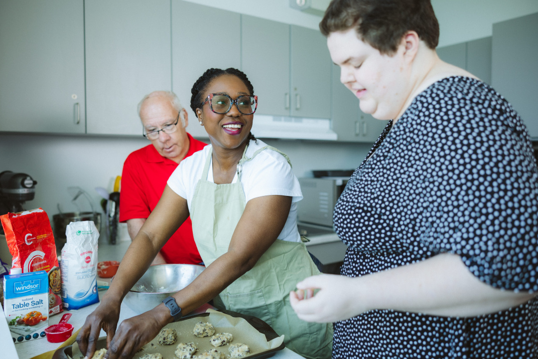 A disability support professional student and two adult Special Olympians make cookies