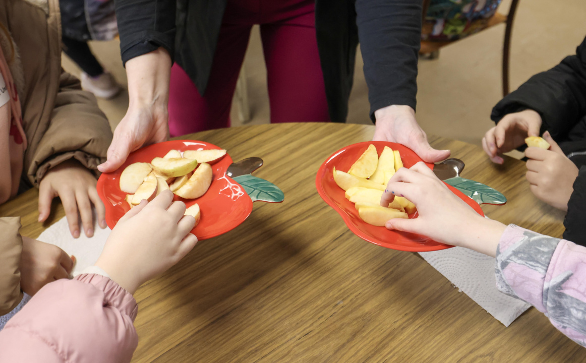 Students hands taking apple slices during a taste test.