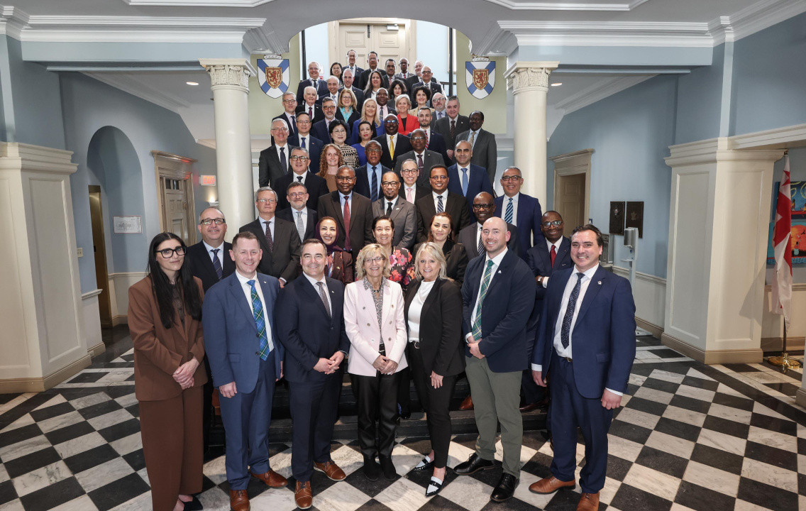 A group of dignitaries pose for a photo on stairs in Province House