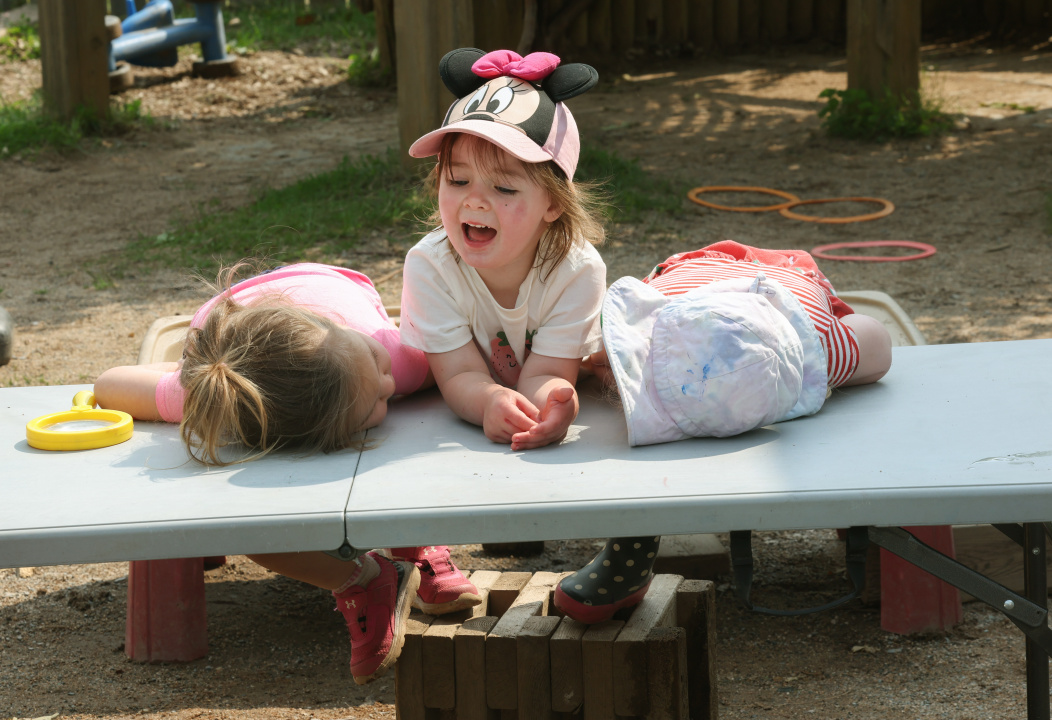 Three preschoolers at a play table.