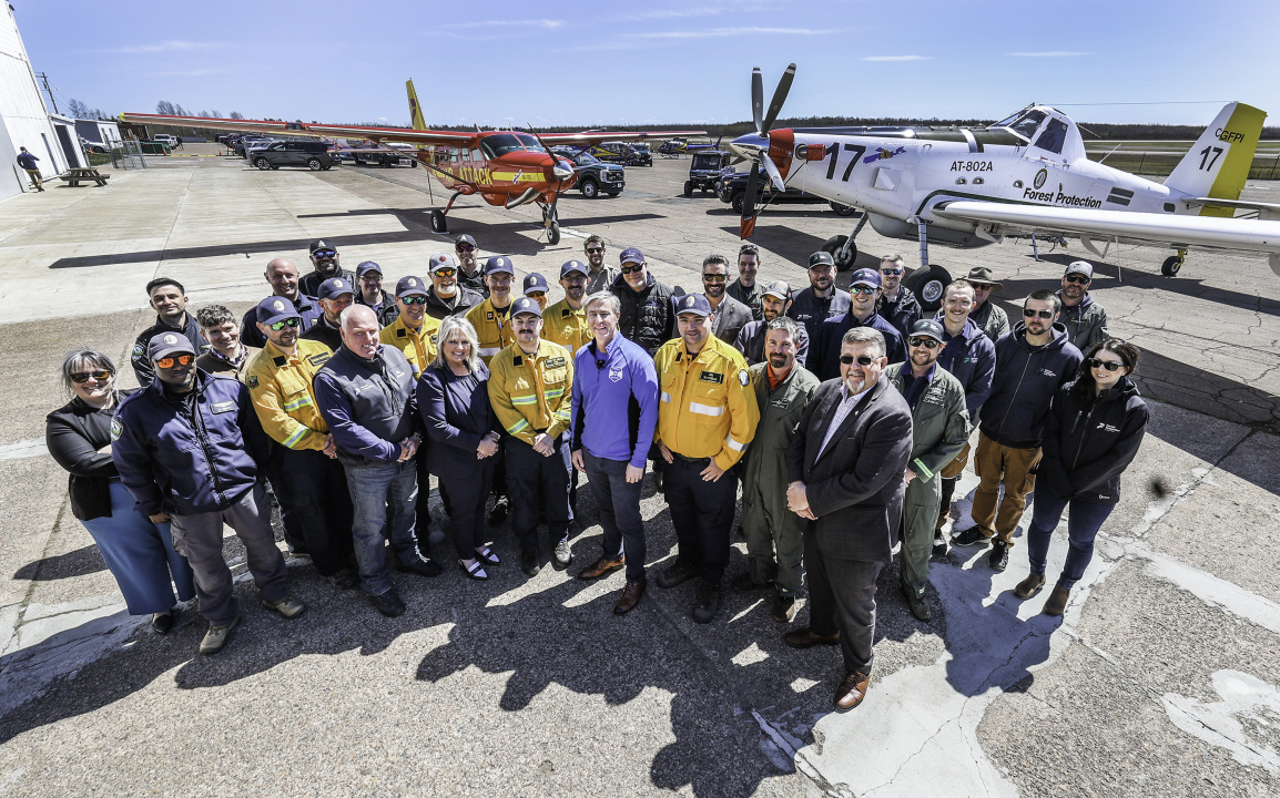 A large group of provincial representatives and crew members with some of the new aircraft.